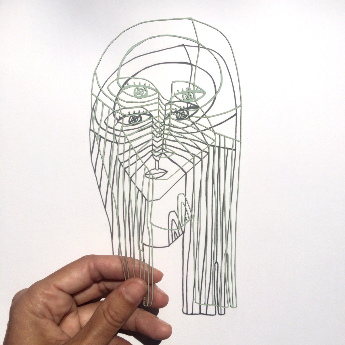 Filigraner mintgrüner Lasercut-Scherenschnitt vor hellem Hintergrund