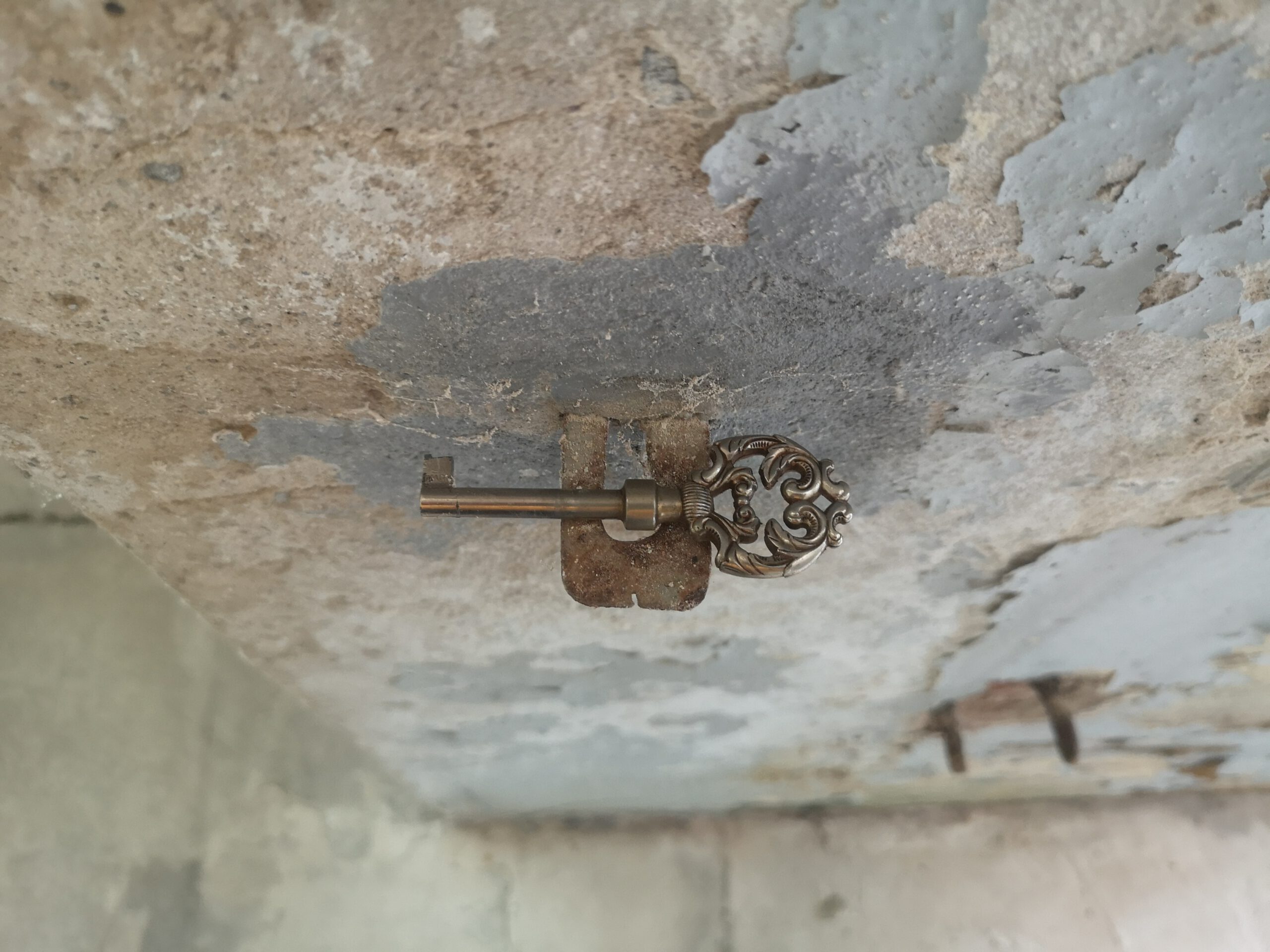 Schlüssel an Wandvorsprung vor abblätternder Wand