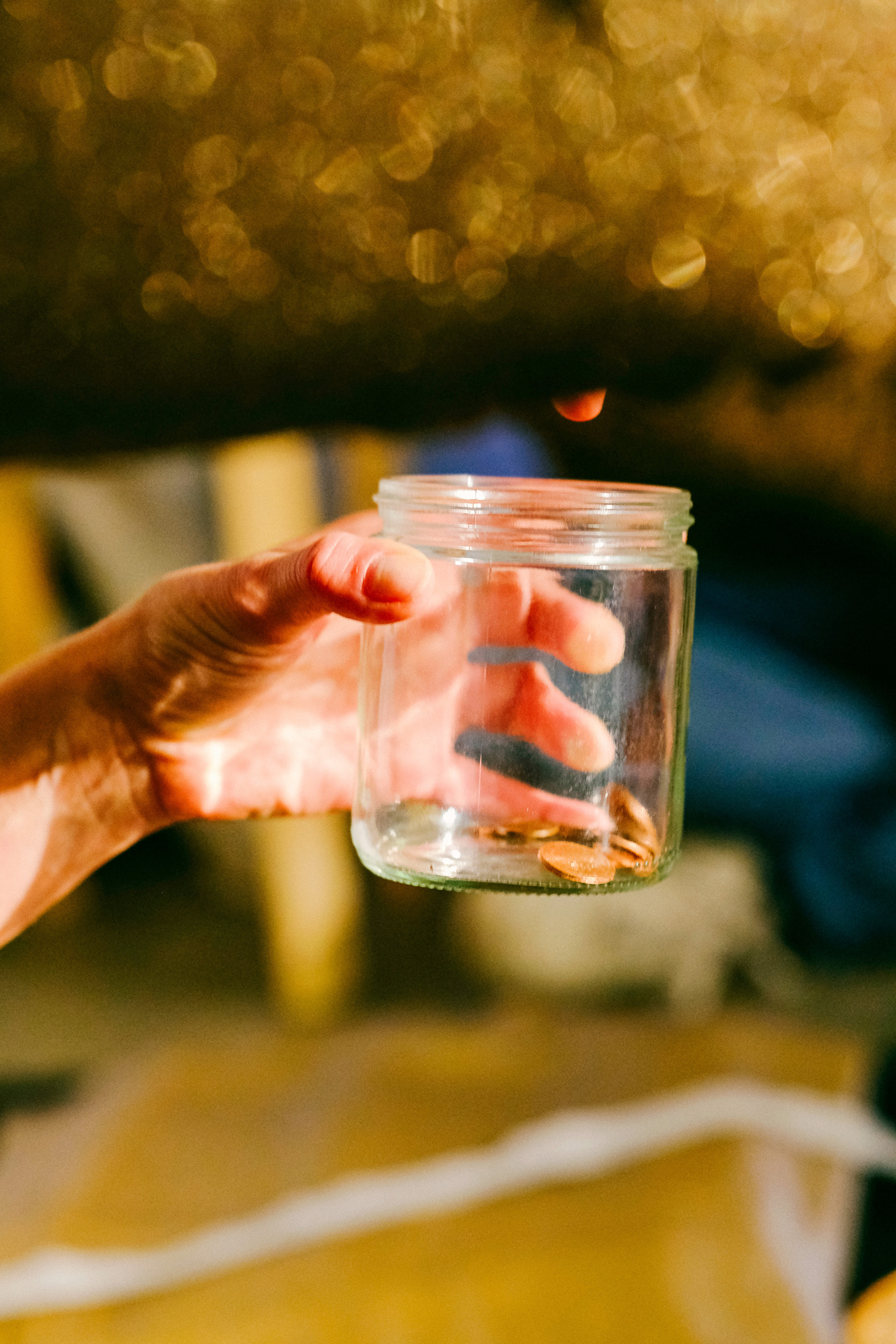 Leeres Glas in Hand gehalten vor unscharf goldenem Hintergrund