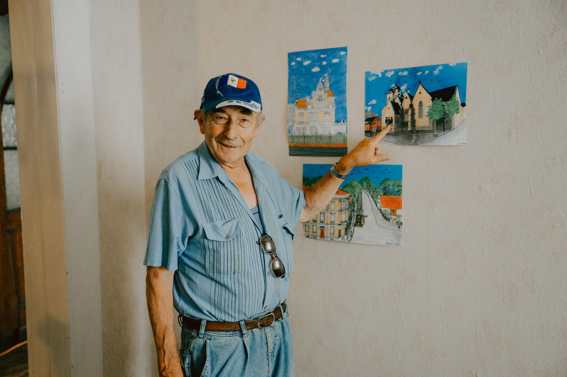 Günther zeigt stolz auf eigene Buntstiftzeichnungen seiner Heimatstadt während einer Ausstellung im Kunsthaus Zeitz.