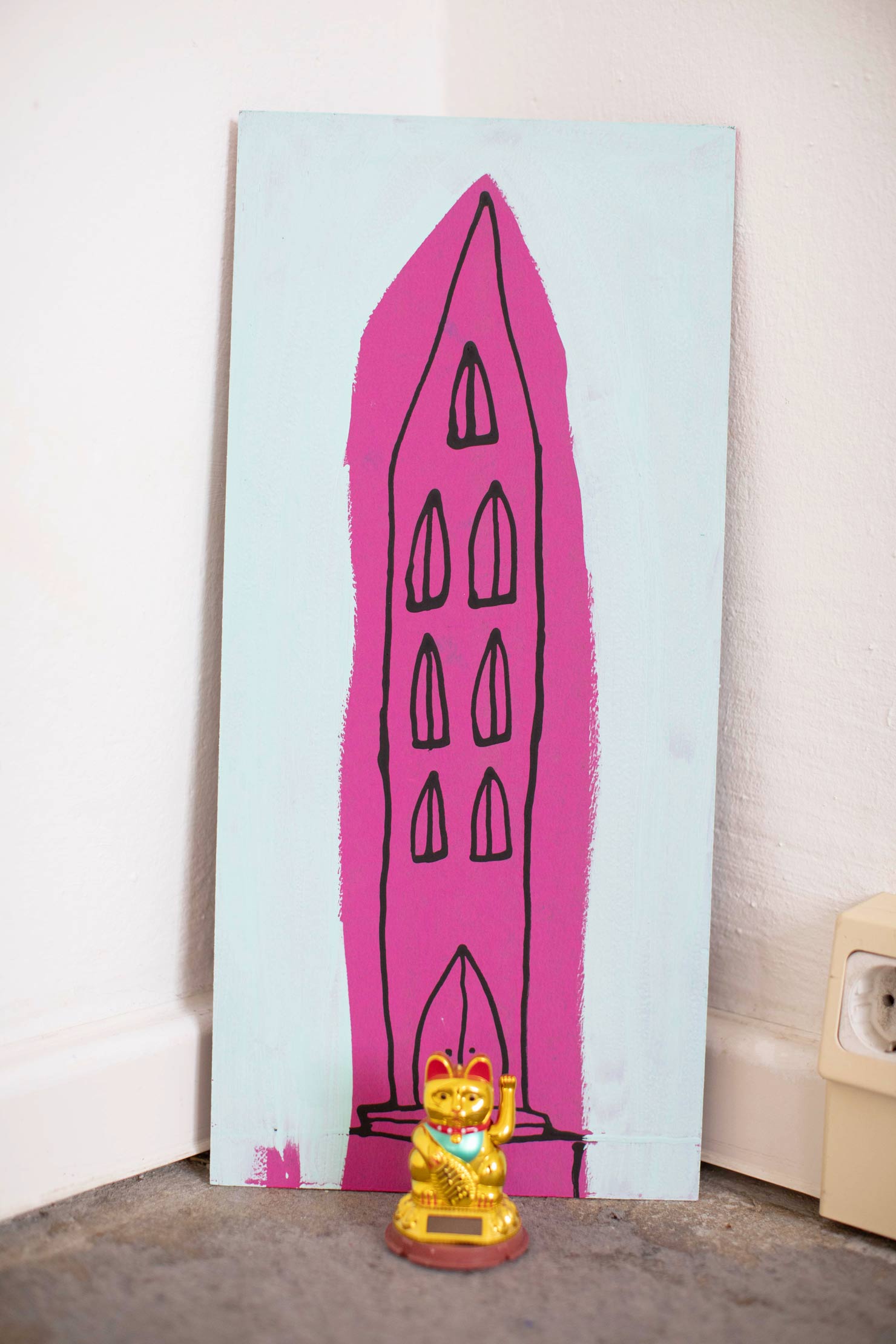 Mint-pinkfarbenes Bild einer abstrahierten Kirche in Raumecke mit goldener Winkekatze