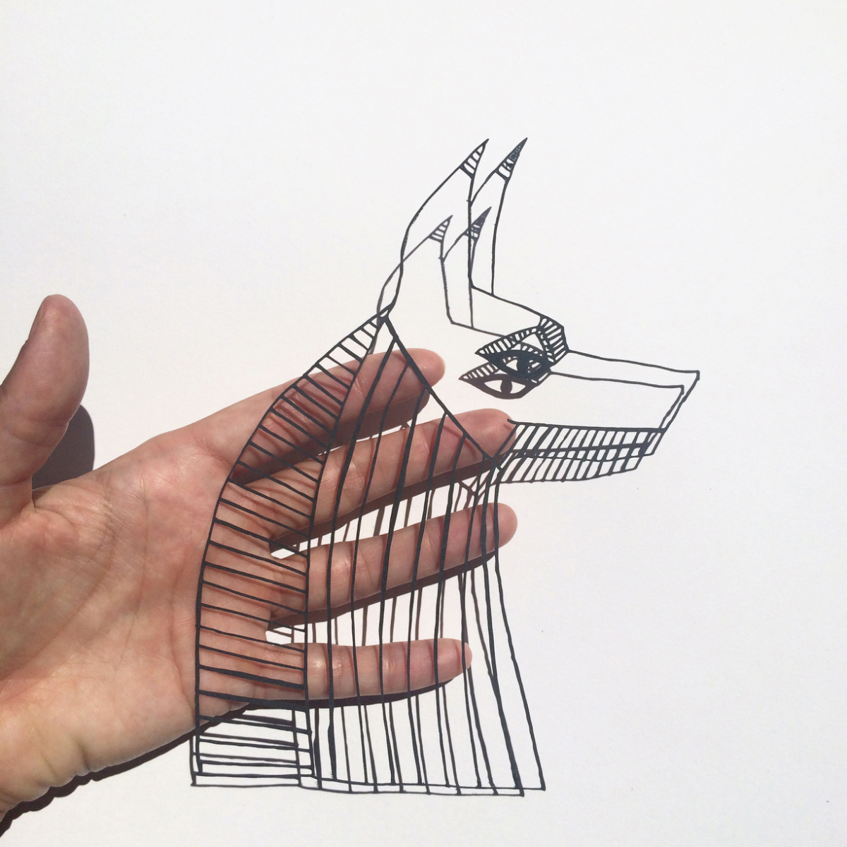 Scherenschnittartiger Lasercut Anubis in Hand gehalten