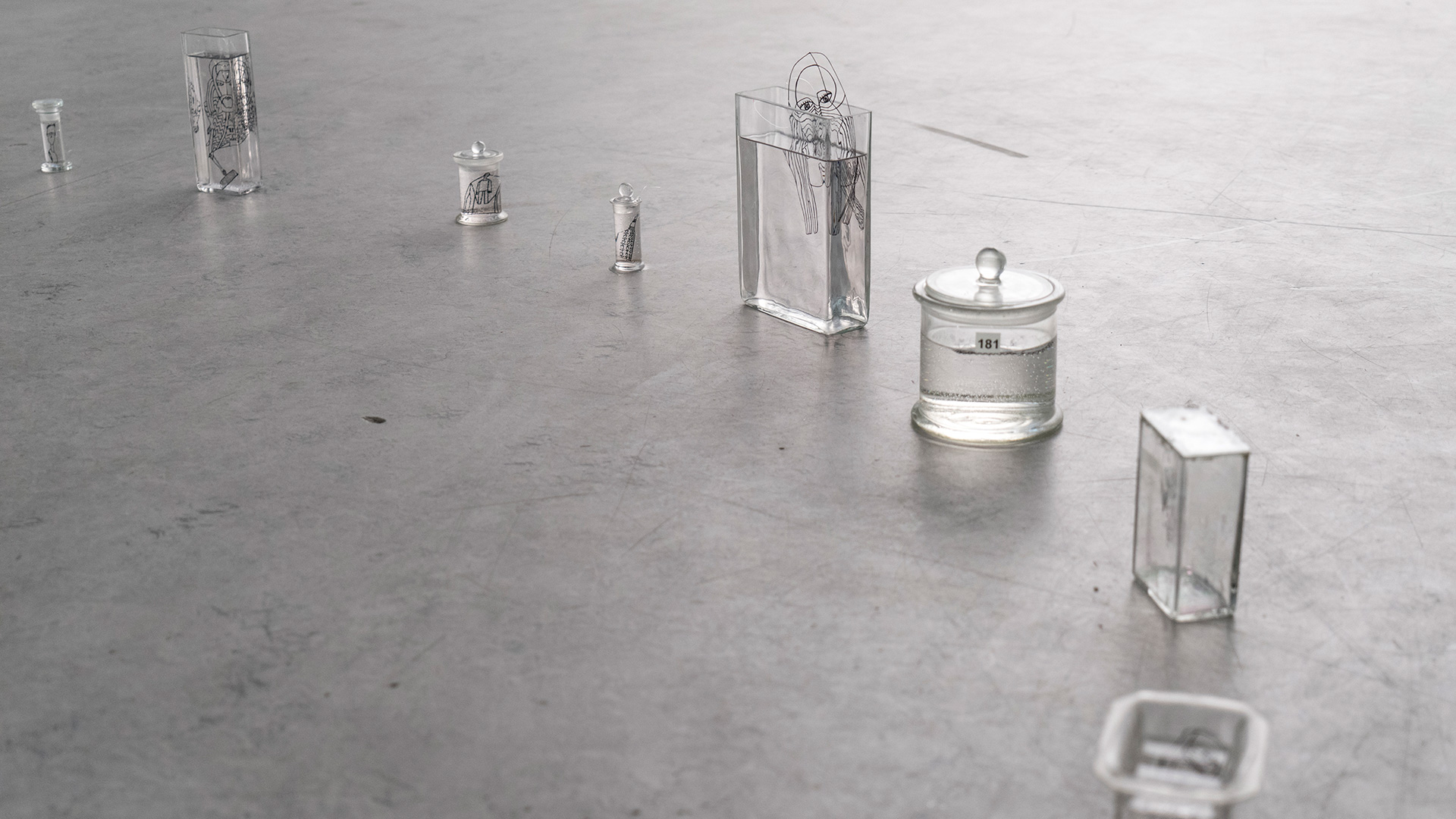 Museumsgläser mit Papierfiguren in Kunstausstellung