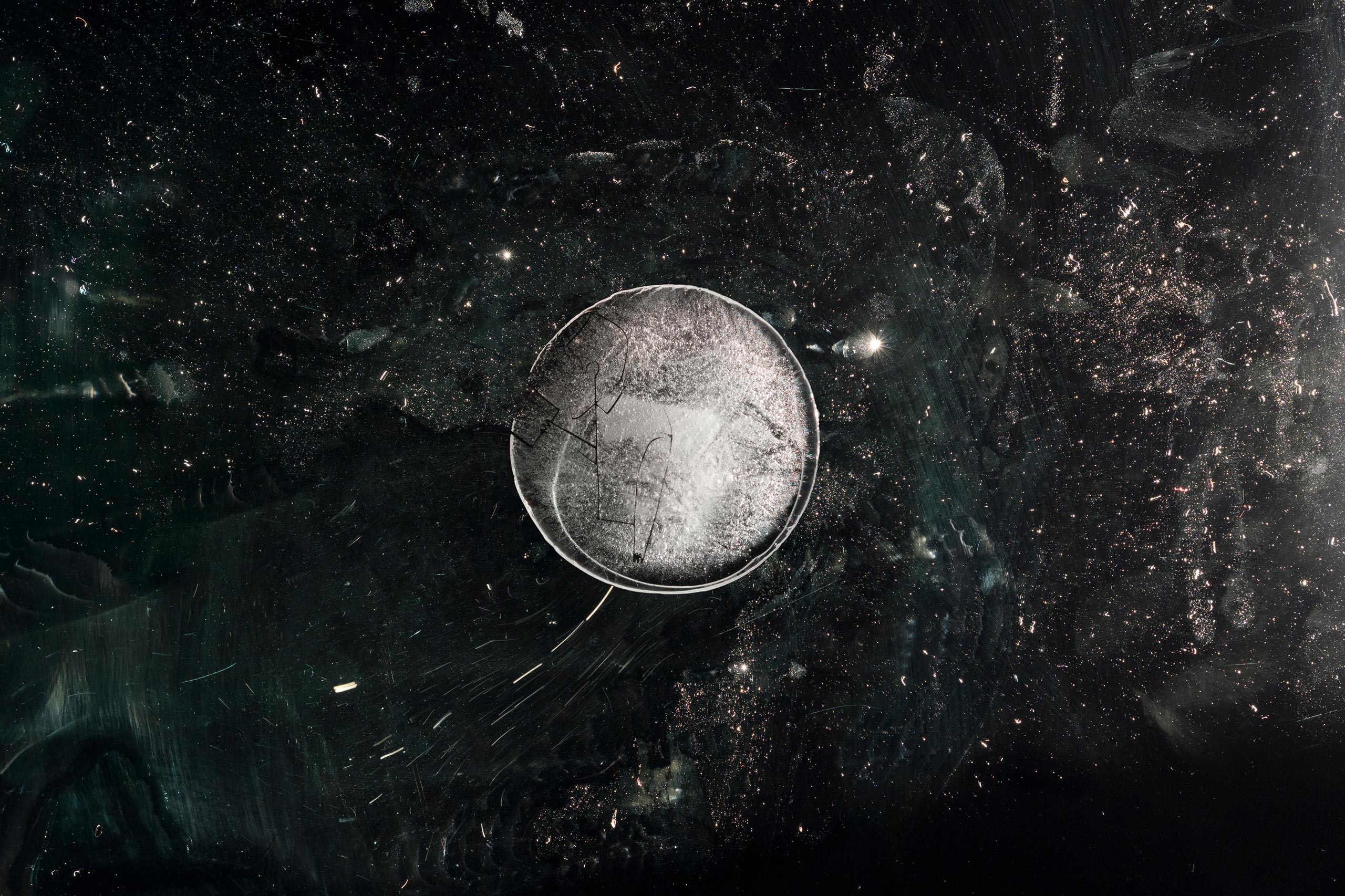 Macro-photography of a semi-transparent fake frozen planet with small figure frozen inside