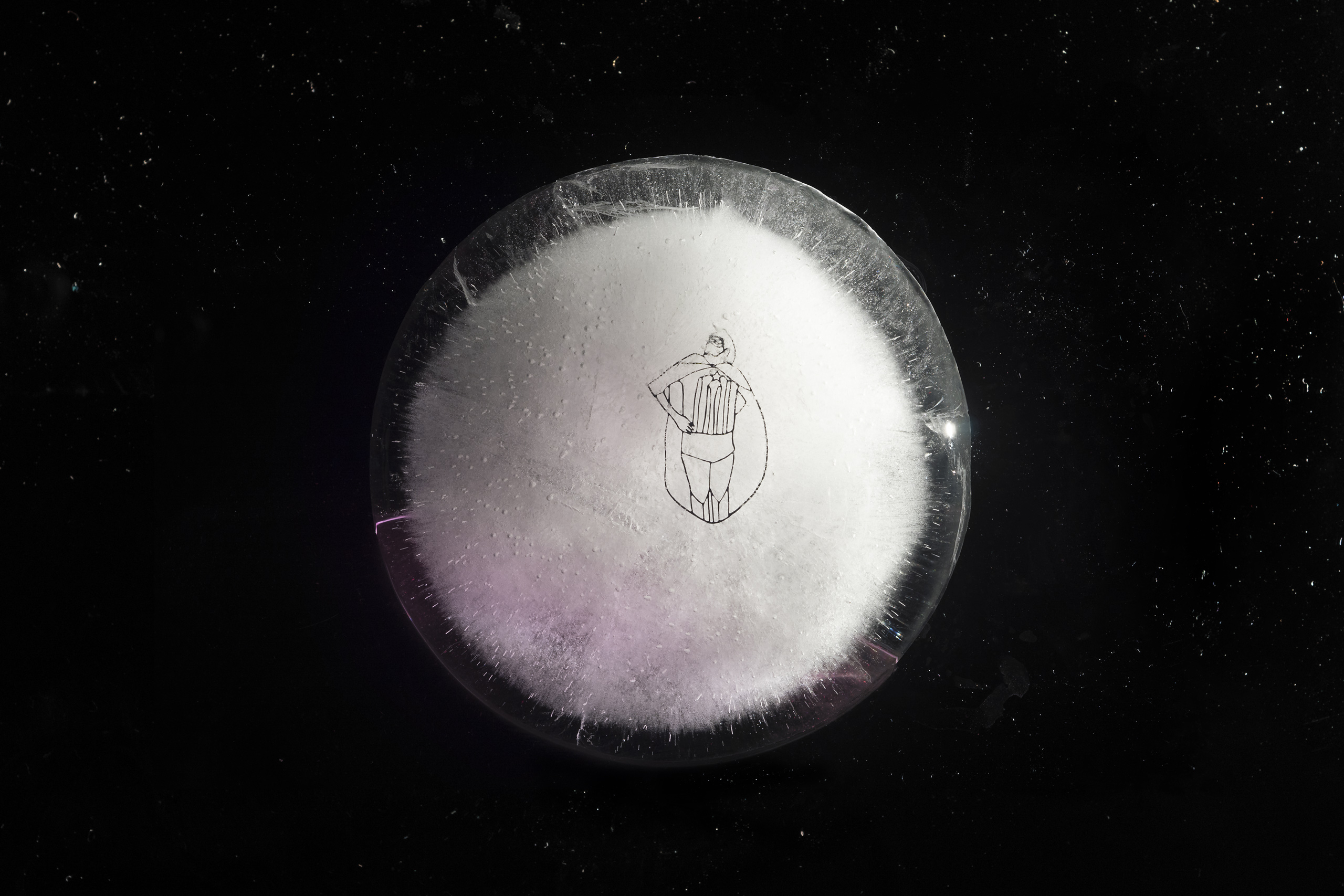 Macro-photography of a fake frozen planet with frozen Superman figure inside.